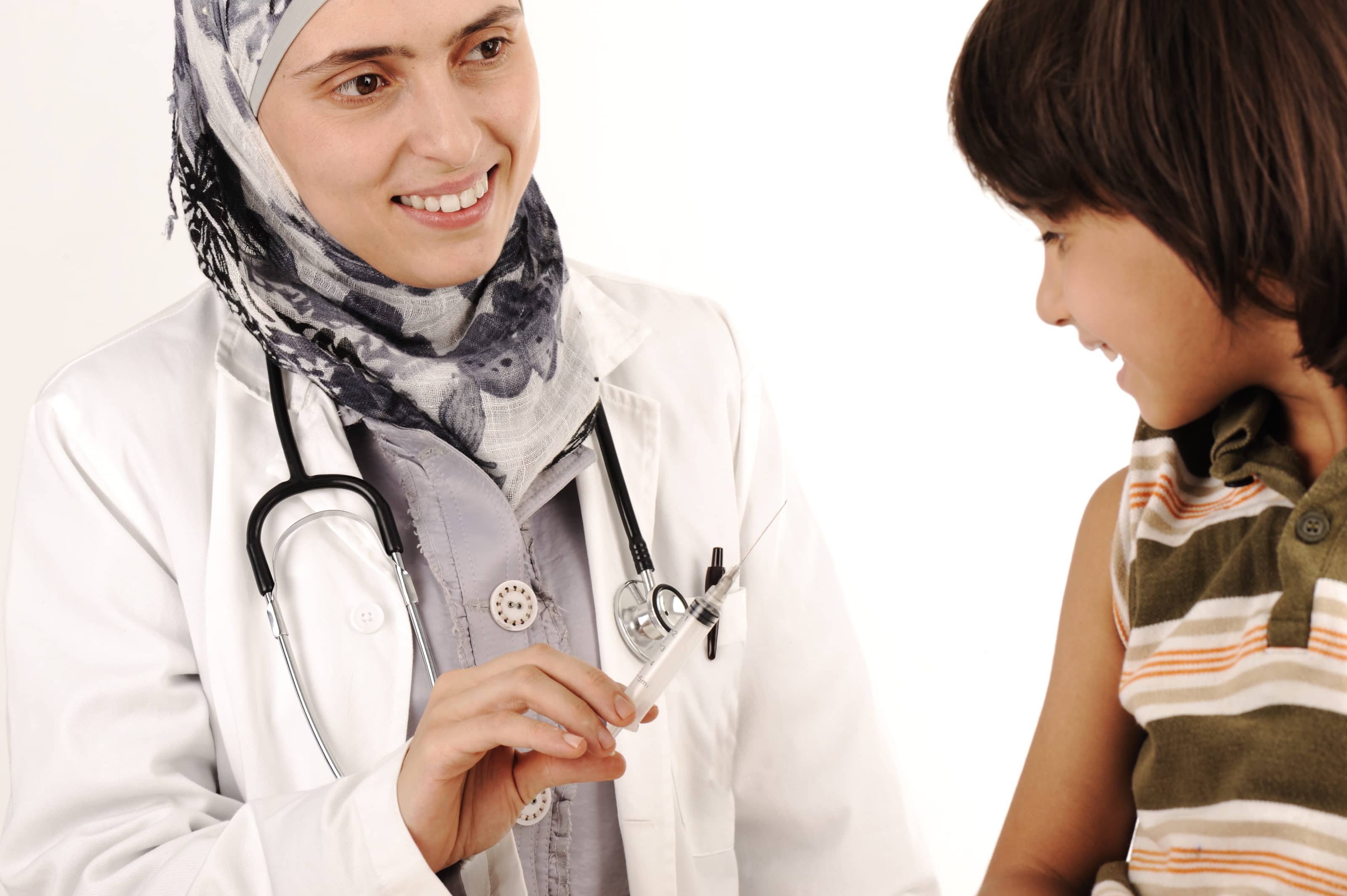 Muslim female doctor in hospital giving an injection to a little boy